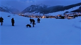 La comitiva sulla neve e Livigno con le luci che si accendono al crepuscolo